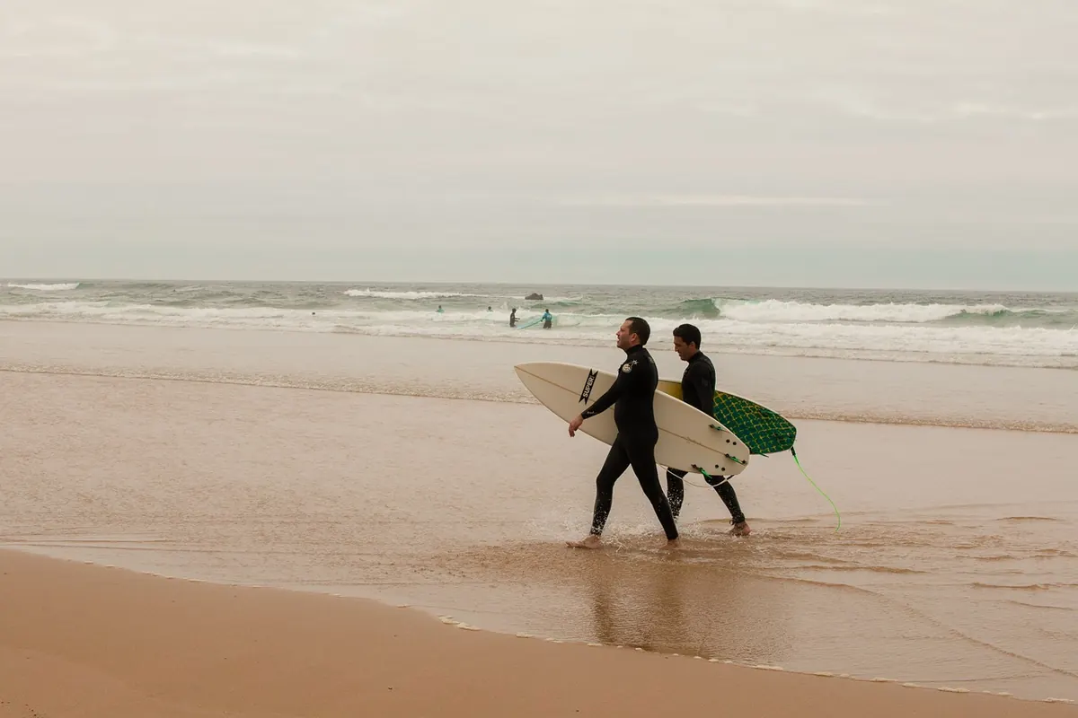 Surfers walking along a beach