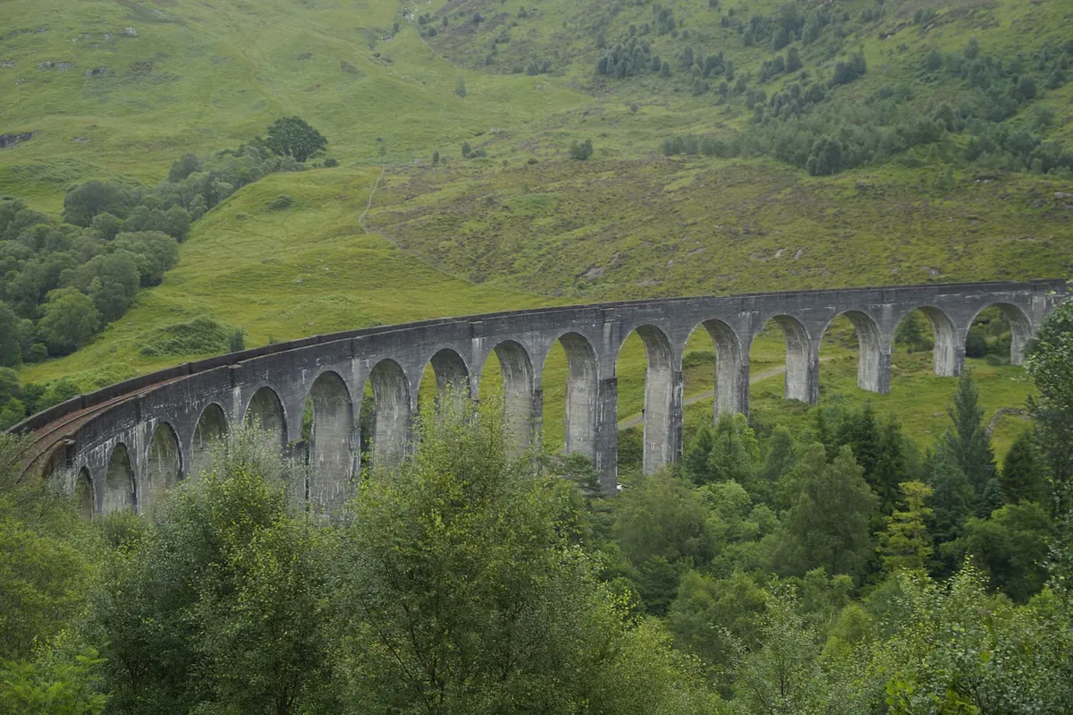A curved stone railway viaduct in the Swiss Alps
