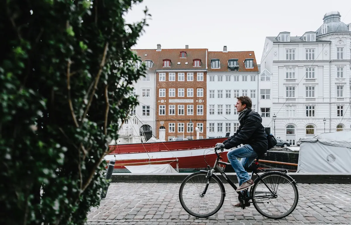 A cyclist passing colourful houses in Copenhagen
